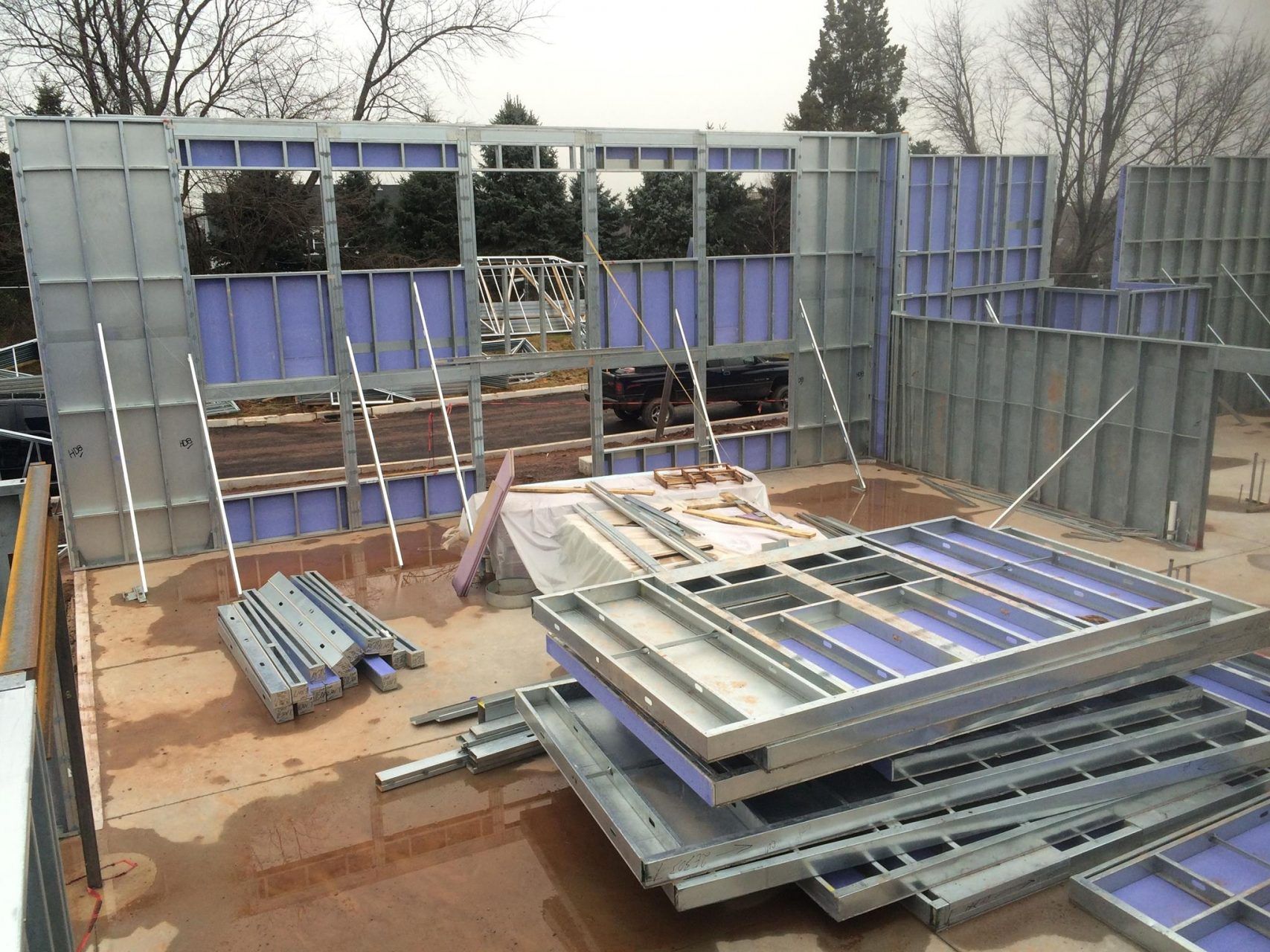 A building under construction with a lot of pieces of steel on the ground.