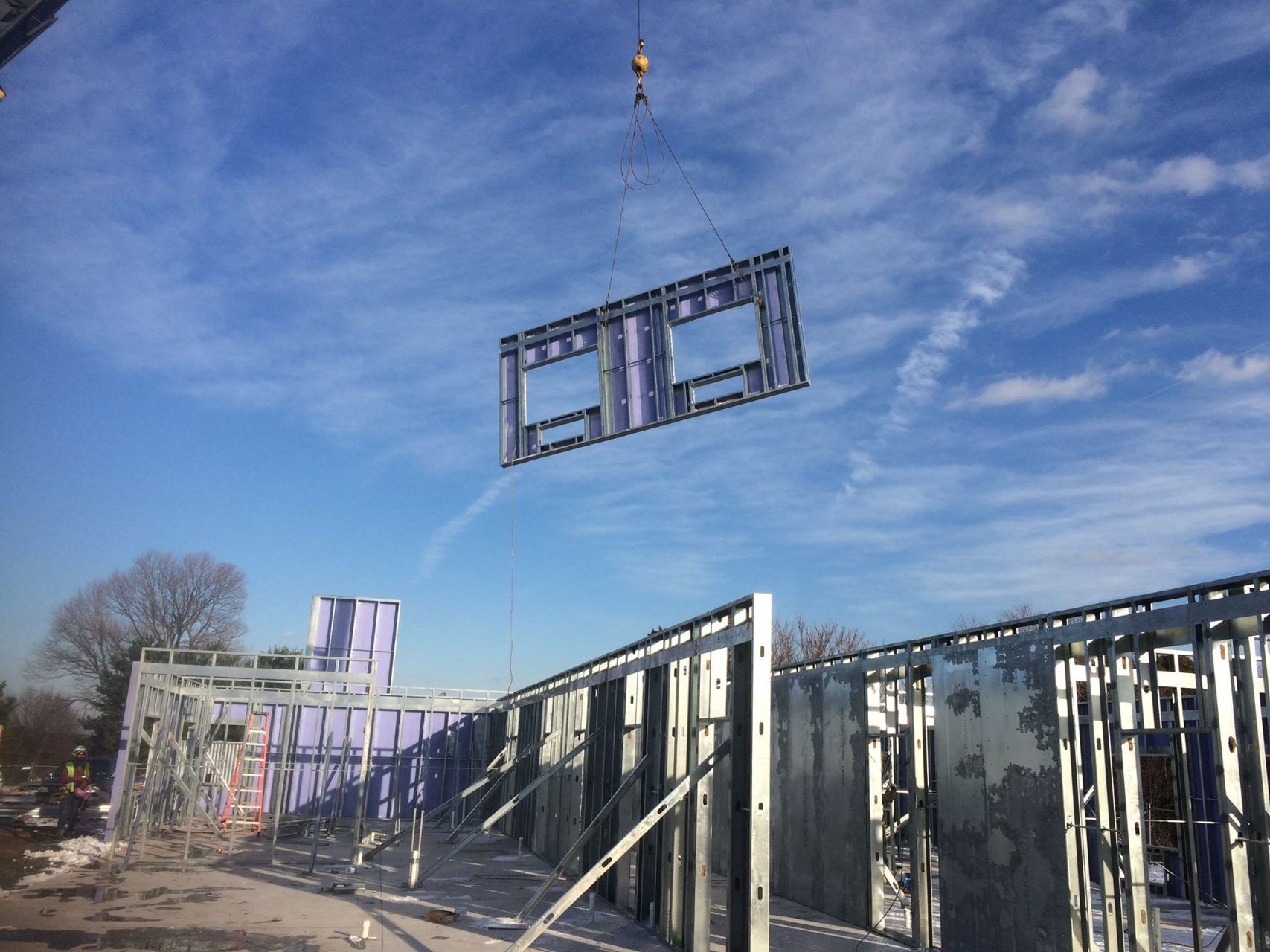 A crane is lifting a piece of steel into the air.