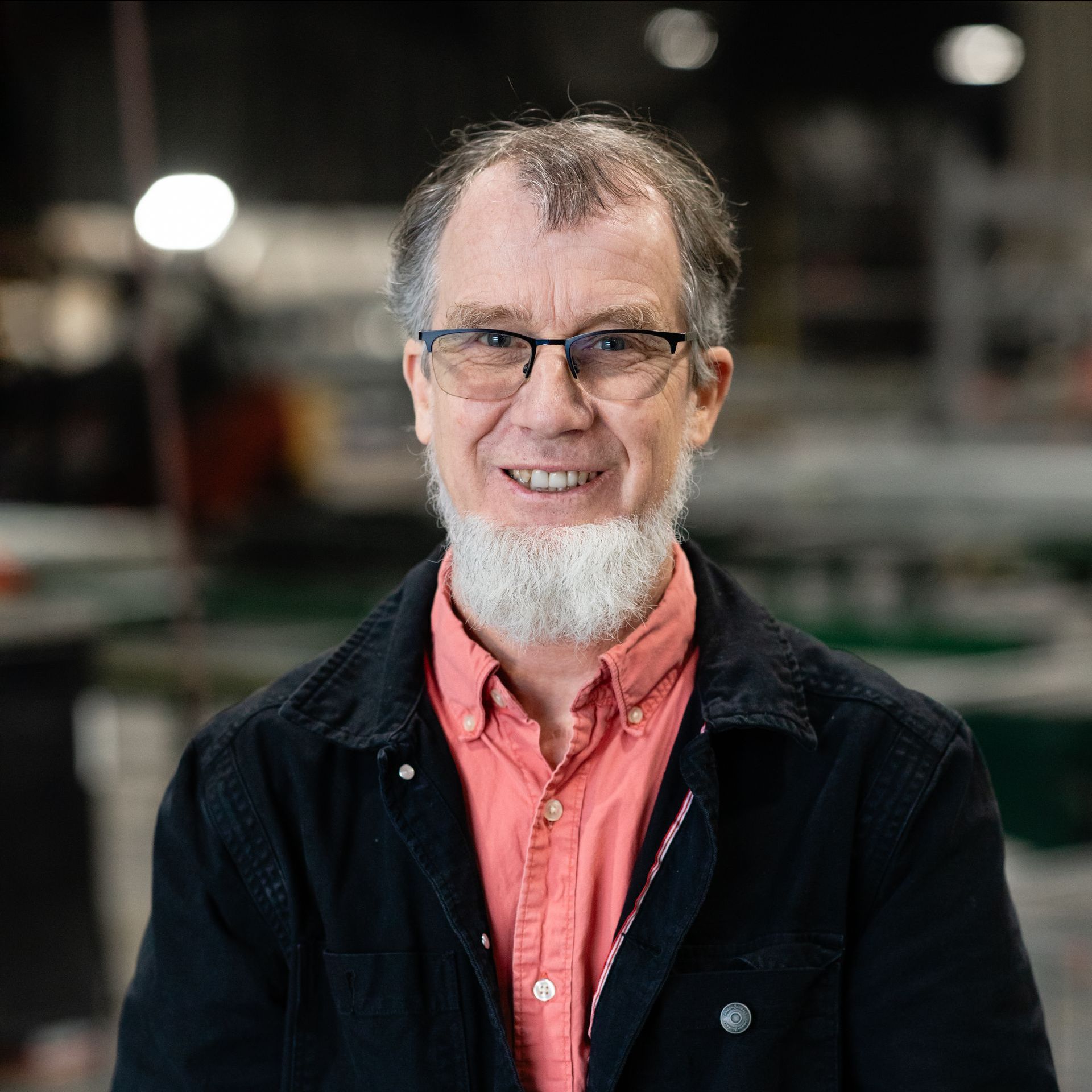 A man with a beard and glasses is smiling.