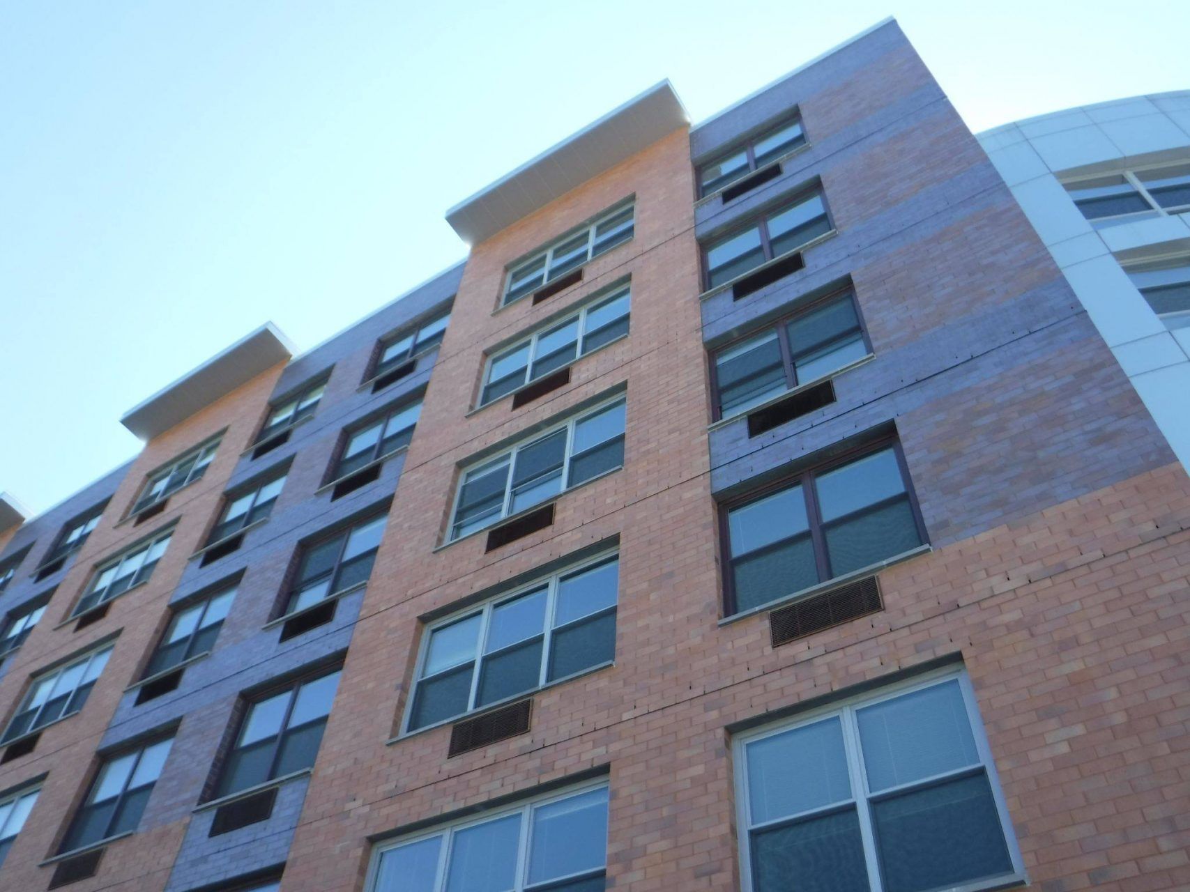 Looking up at a tall brick building with lots of windows.