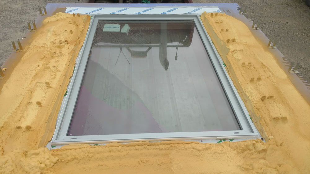 A large window is sitting on top of a pile of sand.