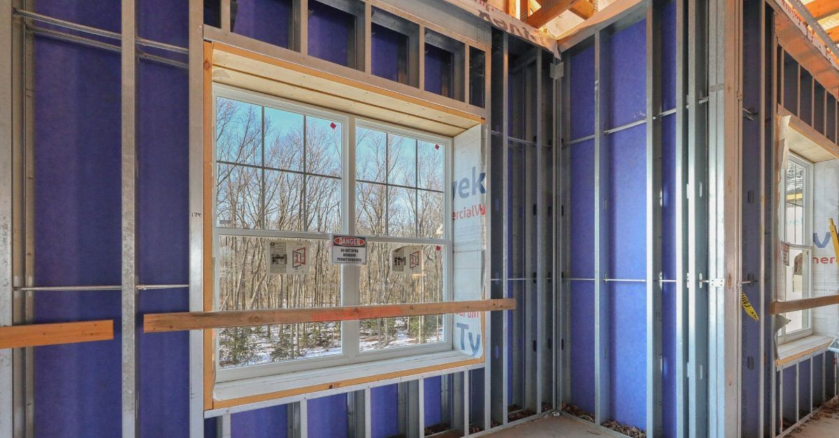 A room in a house under construction with blue walls and a window.