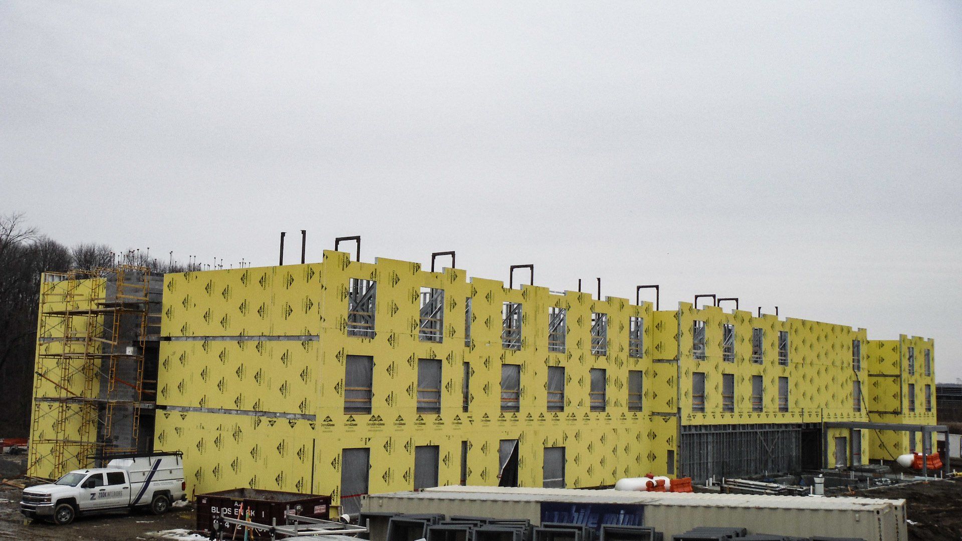 A large building is being built with yellow insulation panels. 