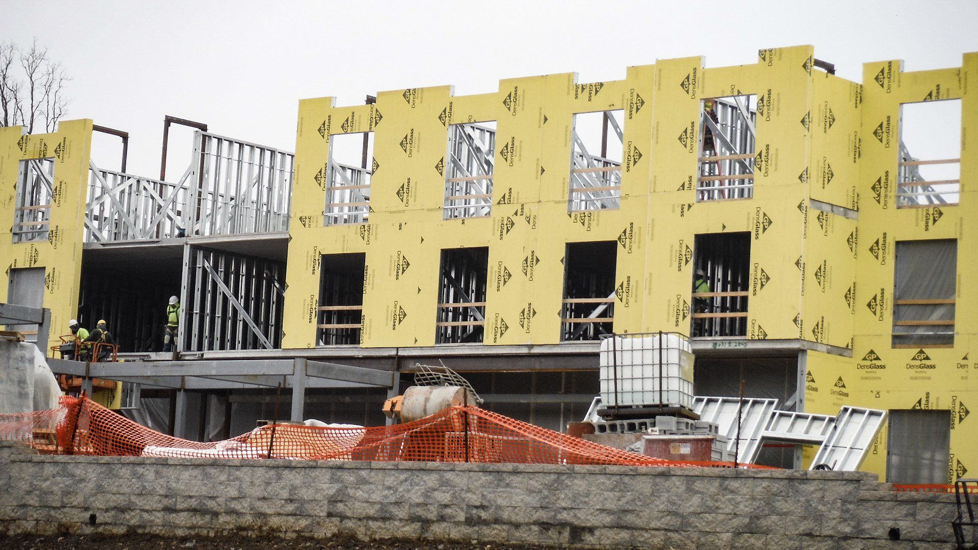 A building that is being constructed containing yellow insblaiont panels. 