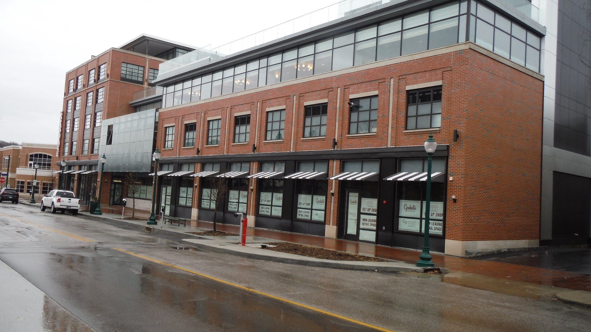 A brick building with a lot of windows beside a wet street.