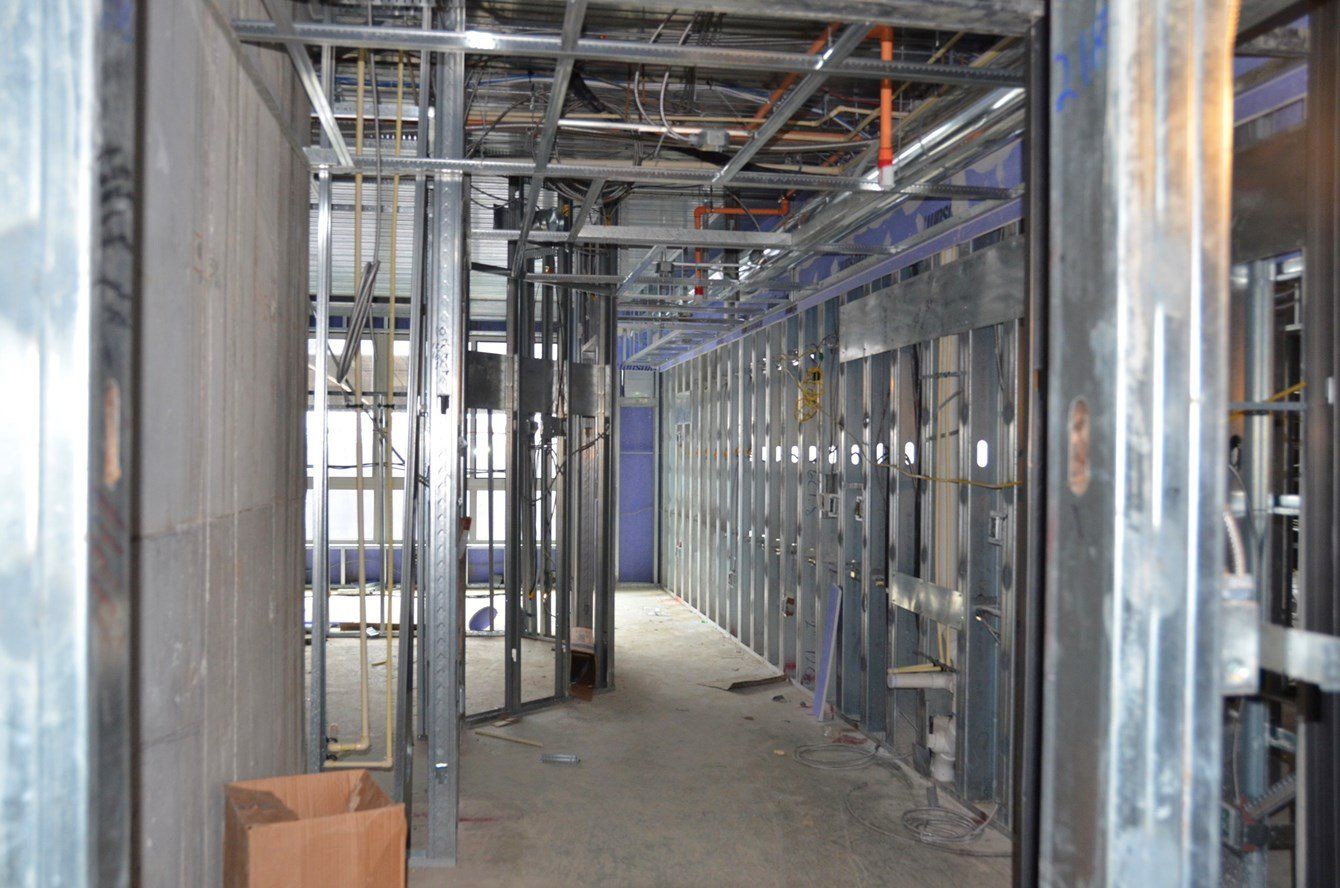 A long hallway in a building under construction with a cardboard box on the floor.