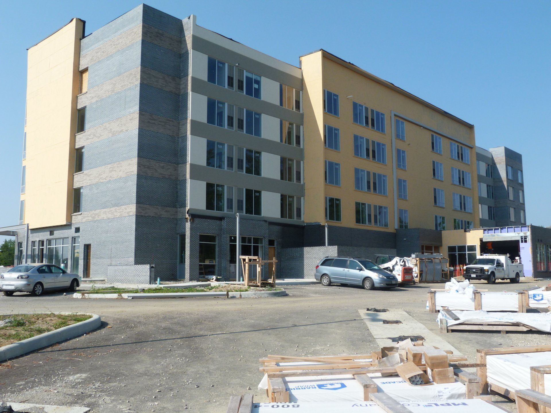A large building under construction with vehicles parked in front of it