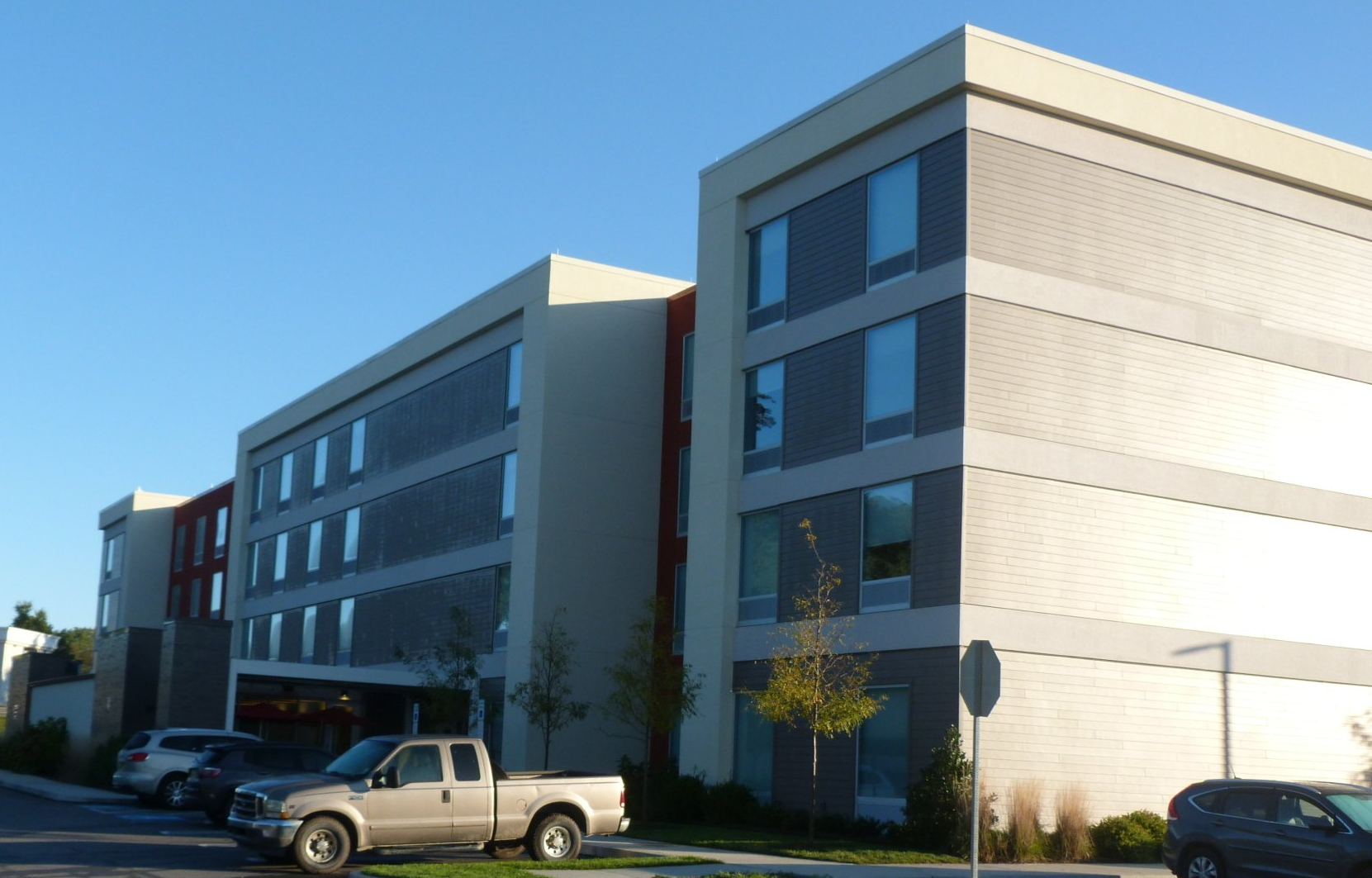 A white truck is parked in front of a large building.