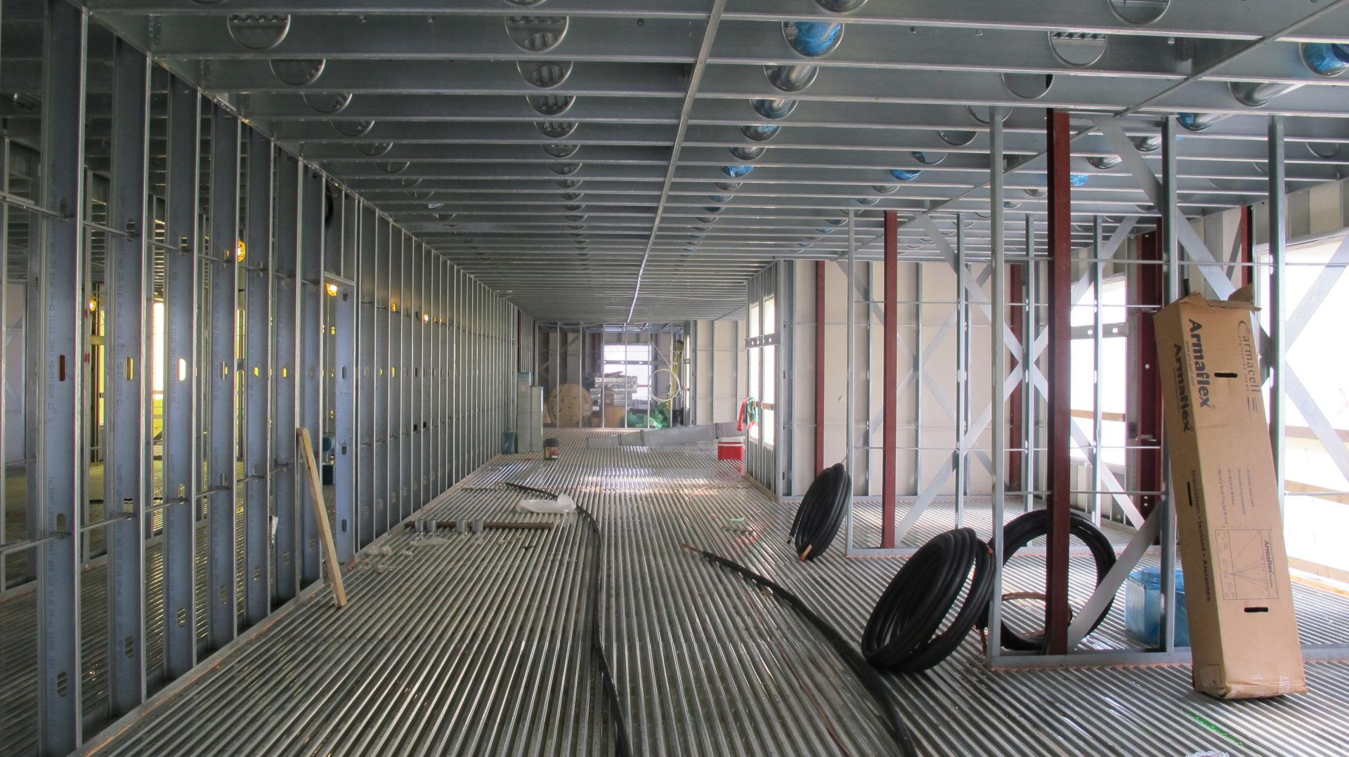 The inside of a building under construction with steel beams and a lot of wires on the floor.