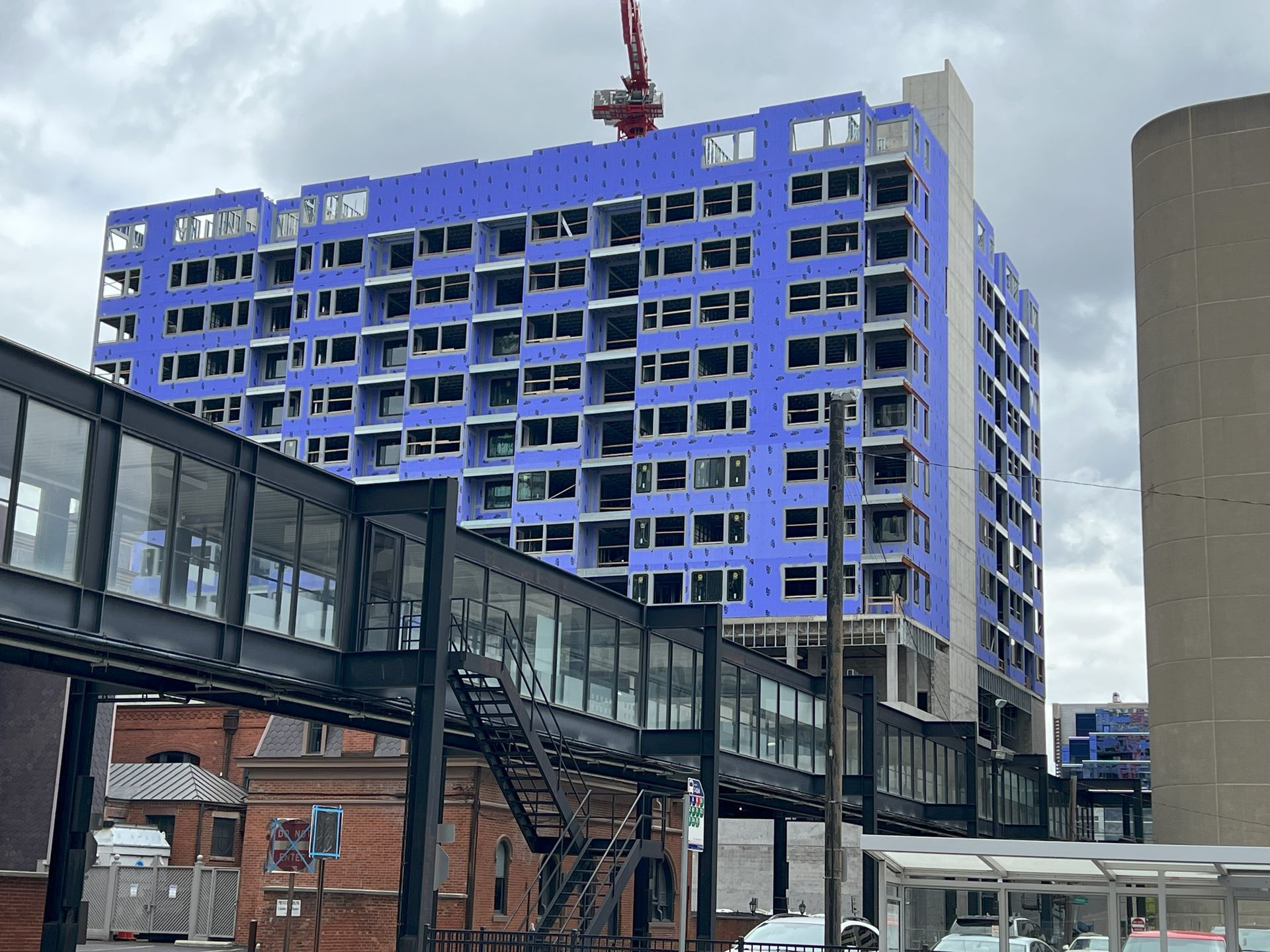 A large blue building is under construction in a city.