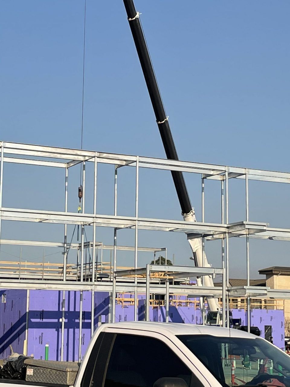 A white truck is parked in front of a building under construction.