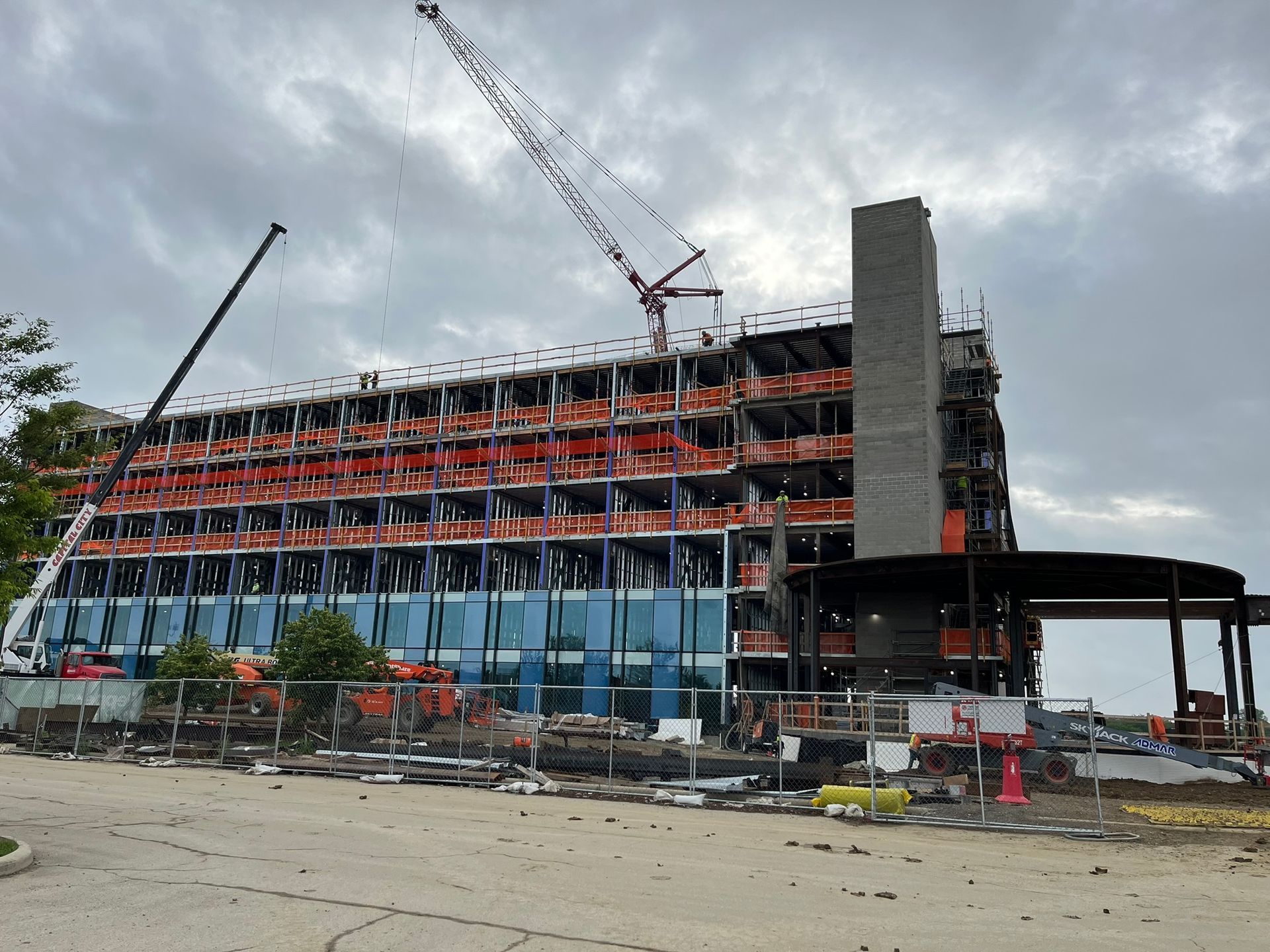 Damaged stadium under construction with cranes, exposed steel beams, and debris in front.