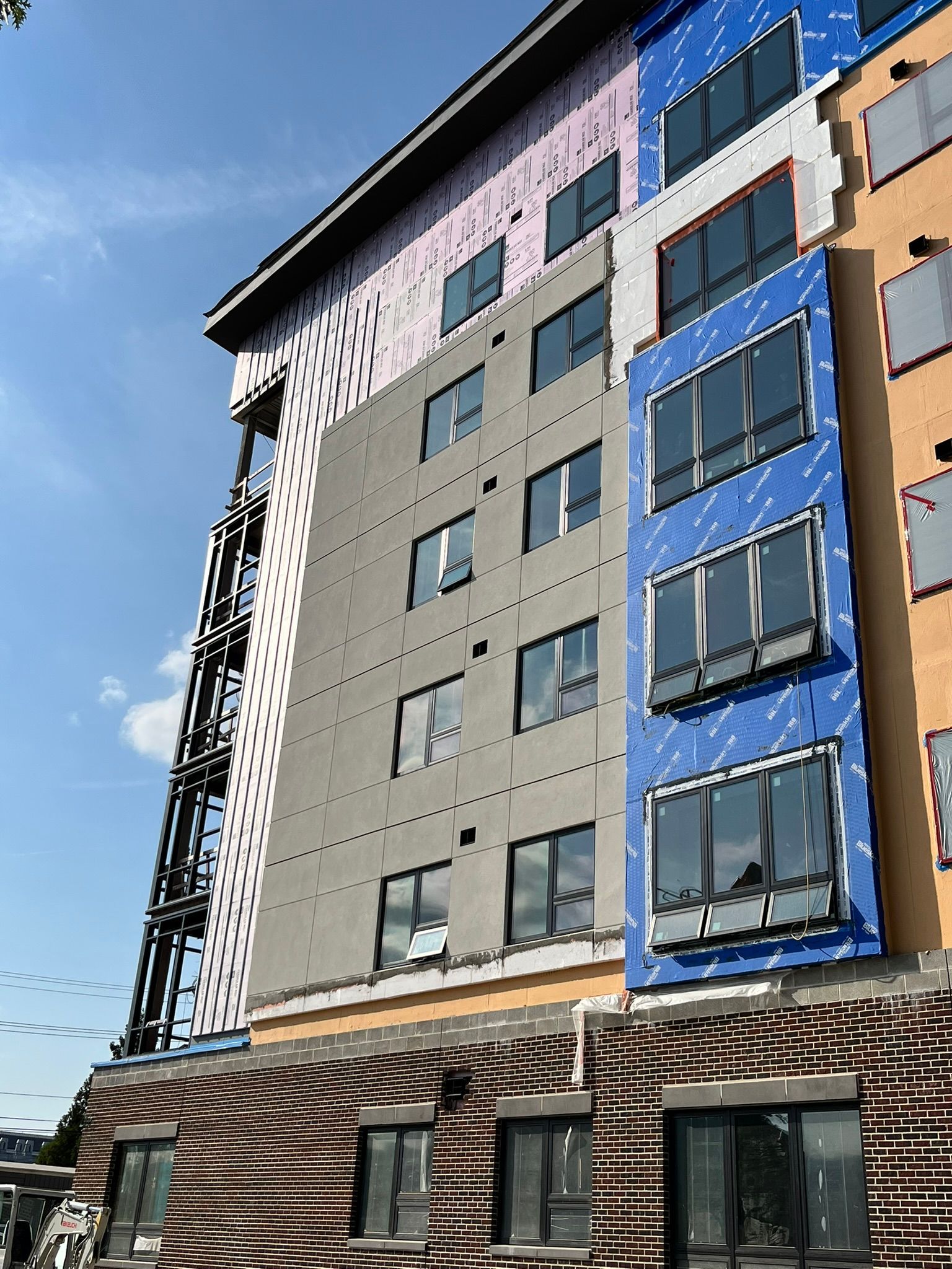 Modern multi-story building with blue and beige panels against a clear sky.