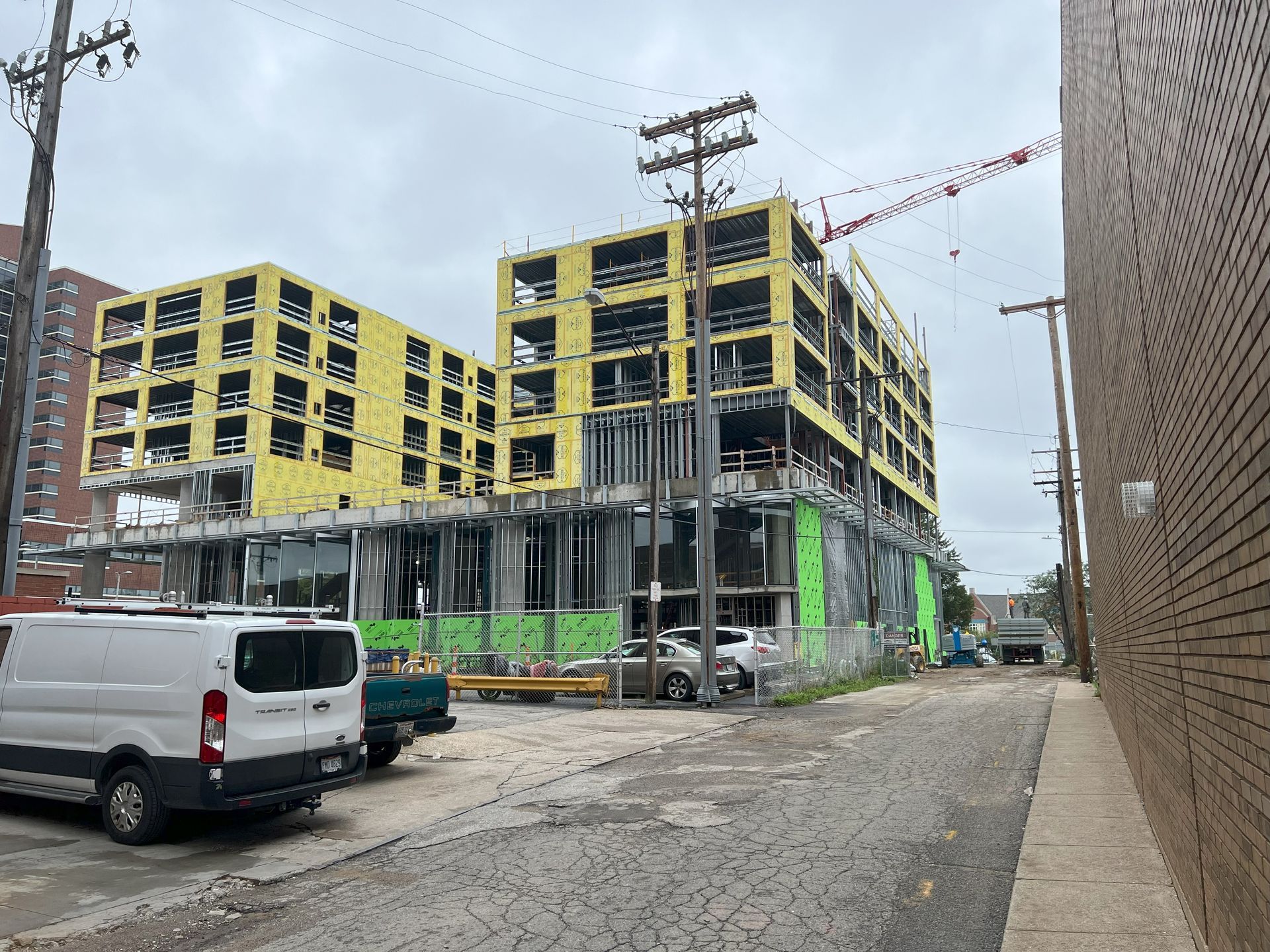 A white van is parked in front of a building under construction.