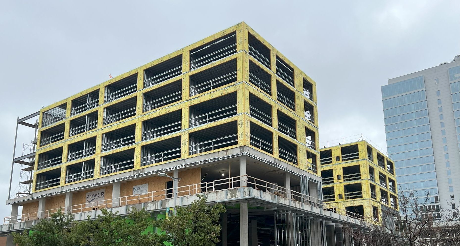 A large building under construction with a skyscraper in the background.
