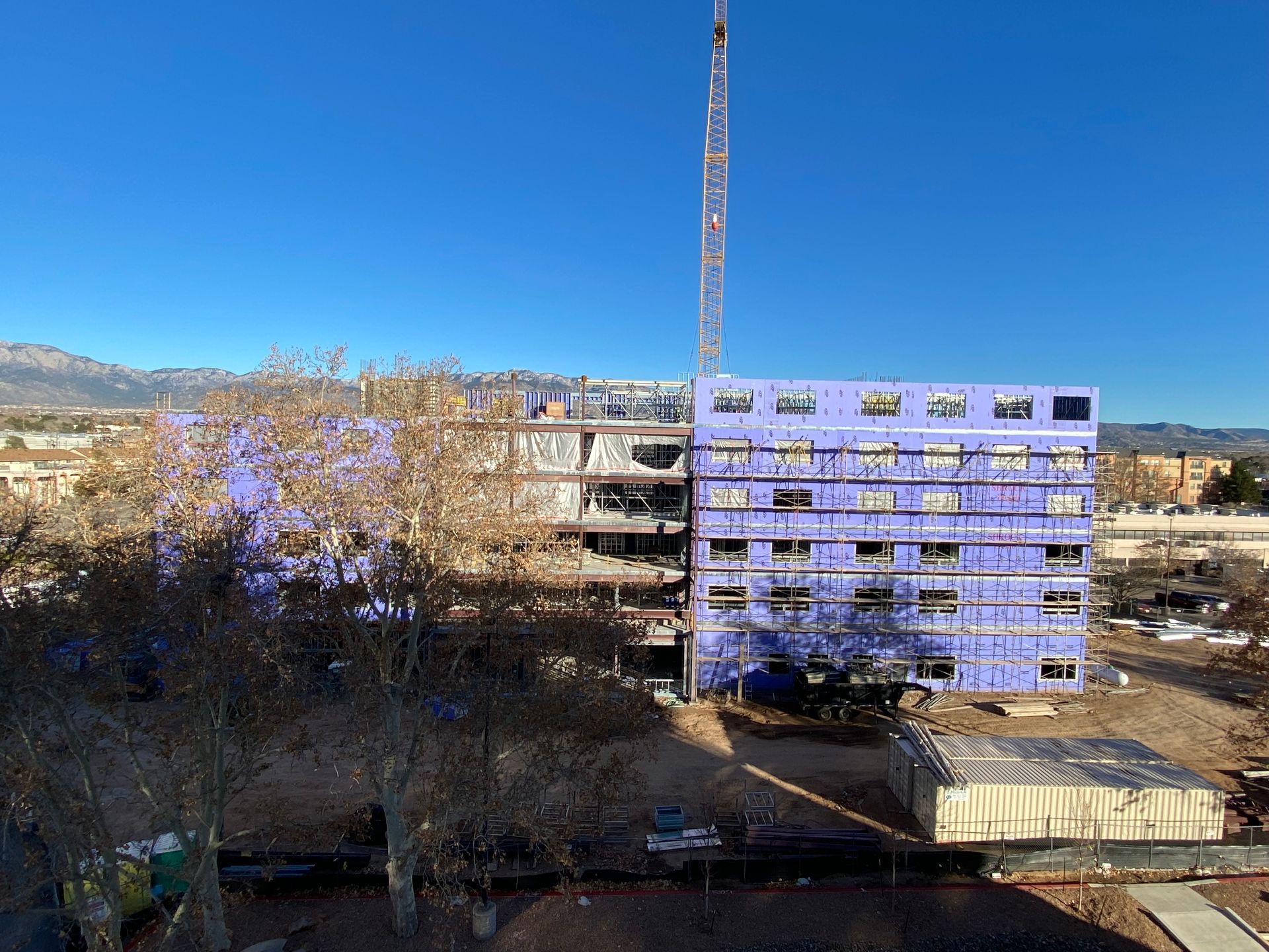 An aerial view of a building under construction with a crane in the background.