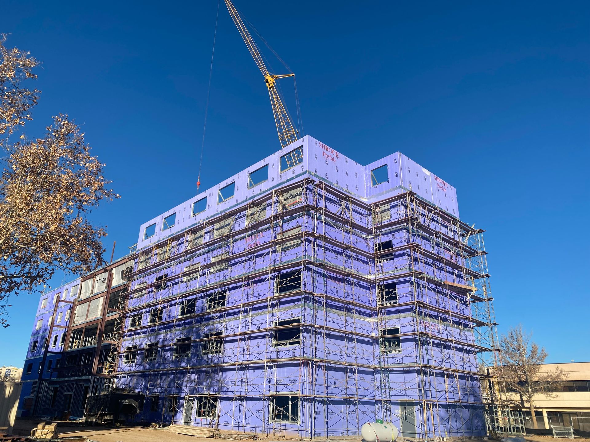 A large building is being built with purple insulation and scaffolding.