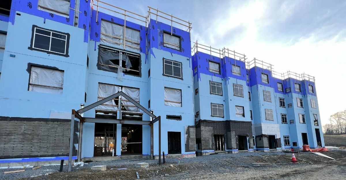 A large blue building under construction with a lot of windows throughout.