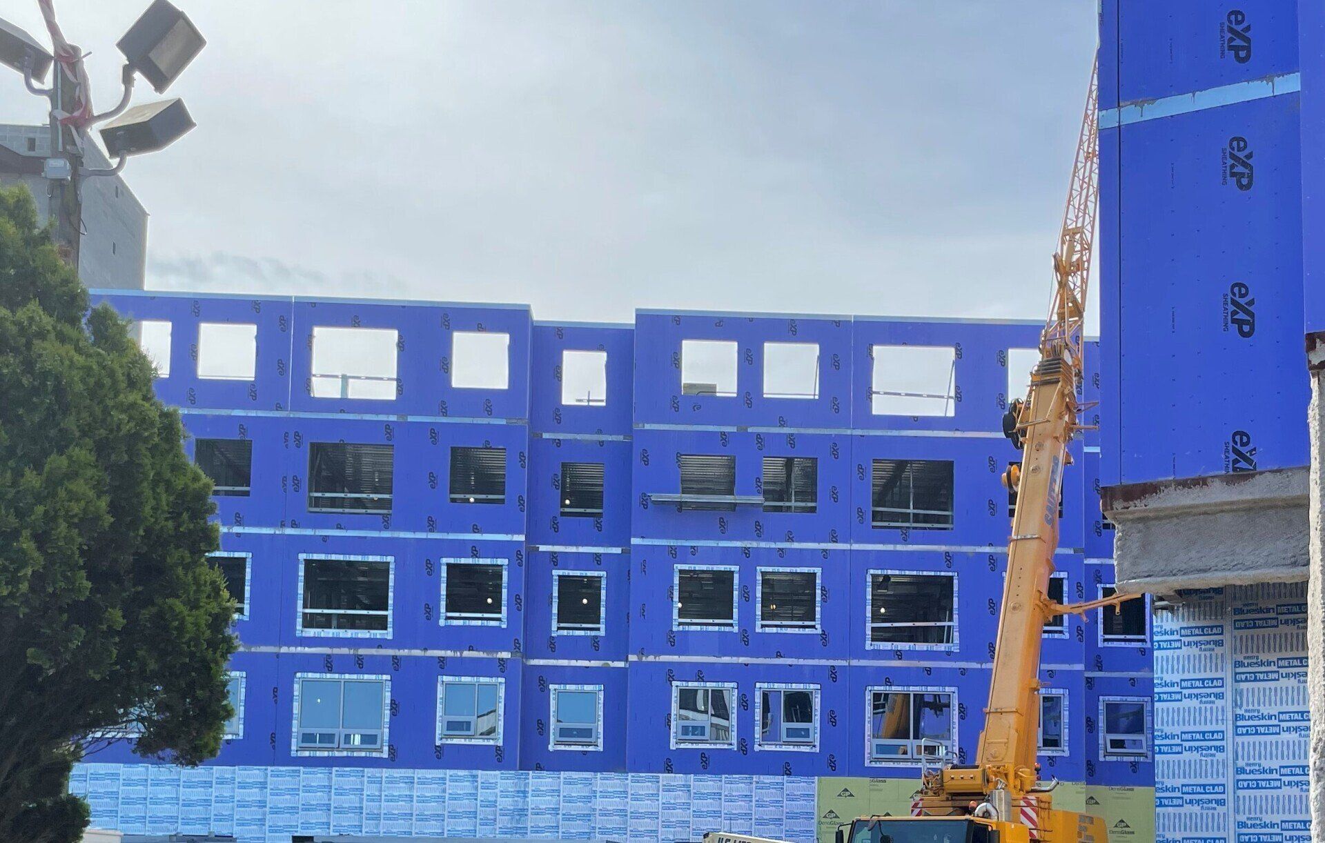 A large blue building with a yellow crane in front of it.