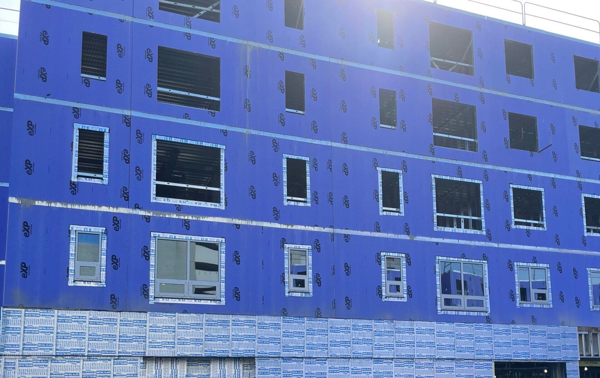 A blue building with a lot of windows under construction.