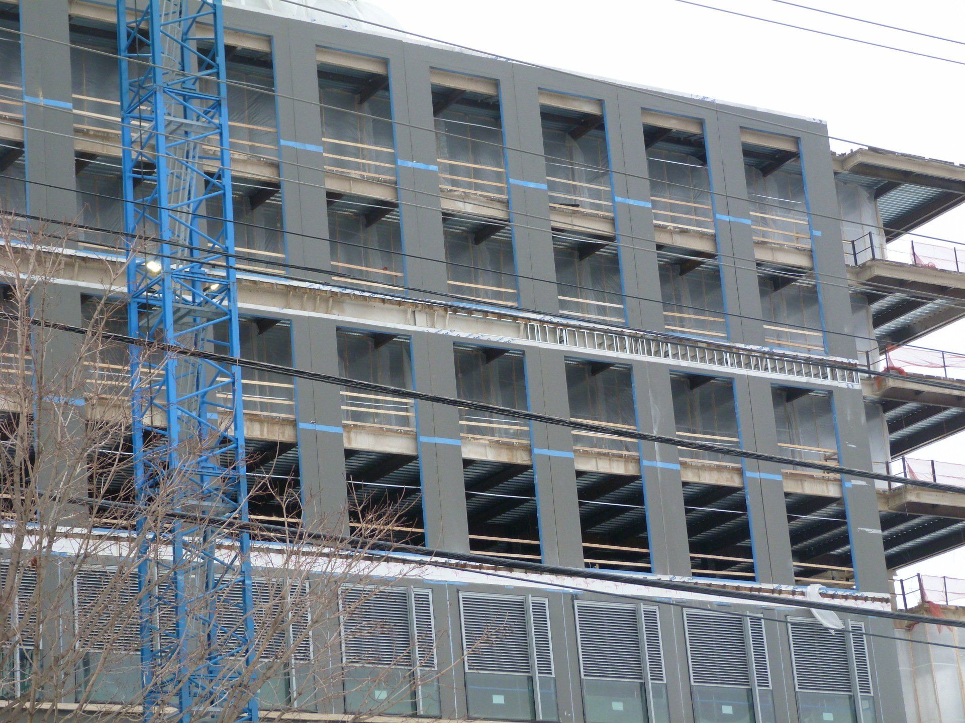 A large building under construction with a blue crane in front of it.