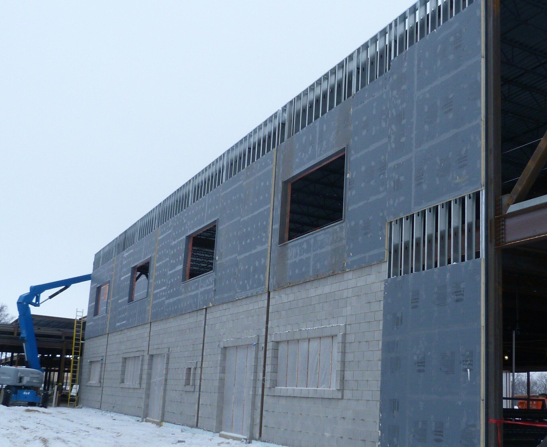 A large building under construction with a blue crane in the background.
