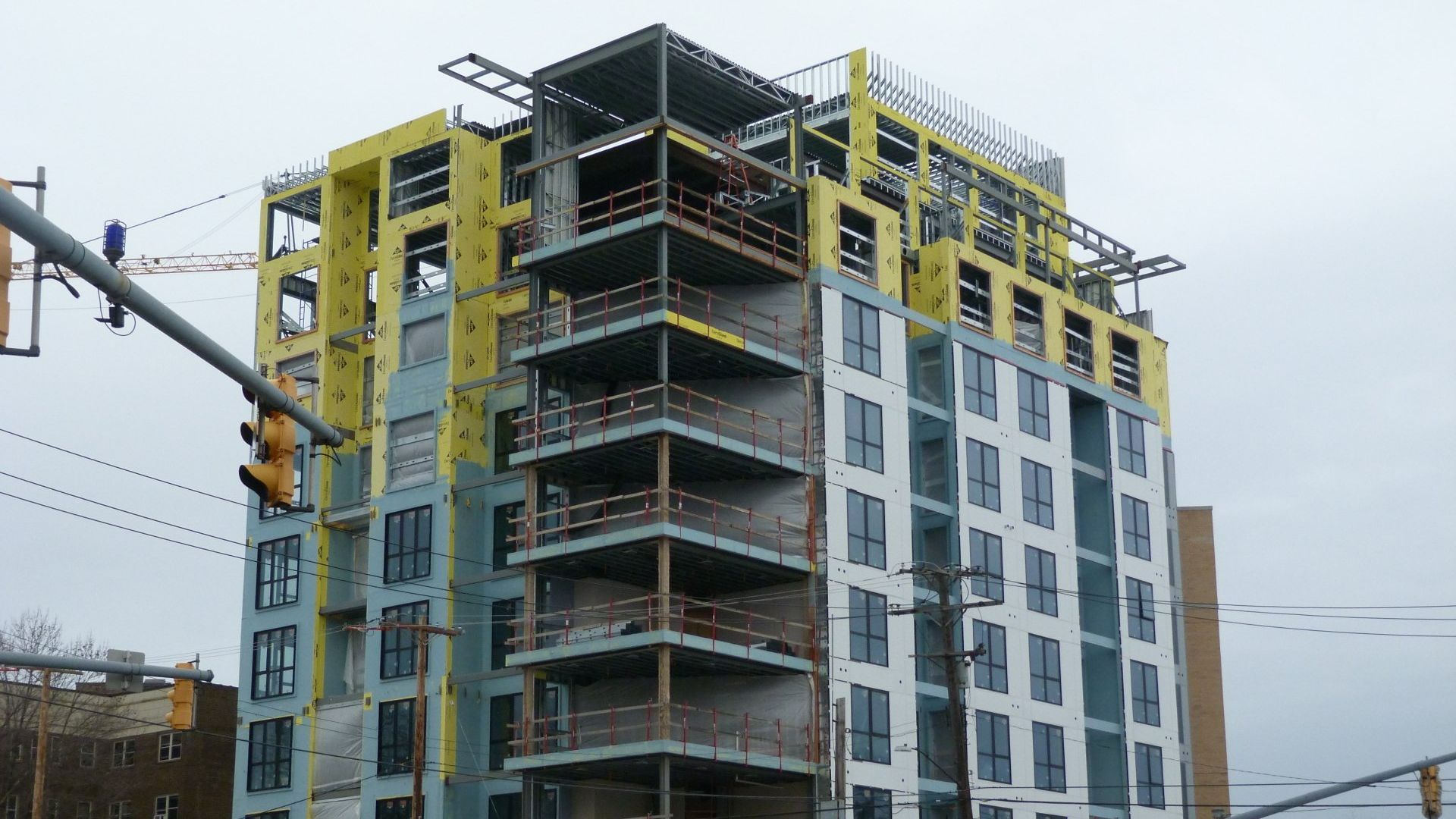 A tall building under construction with a traffic light in front of it