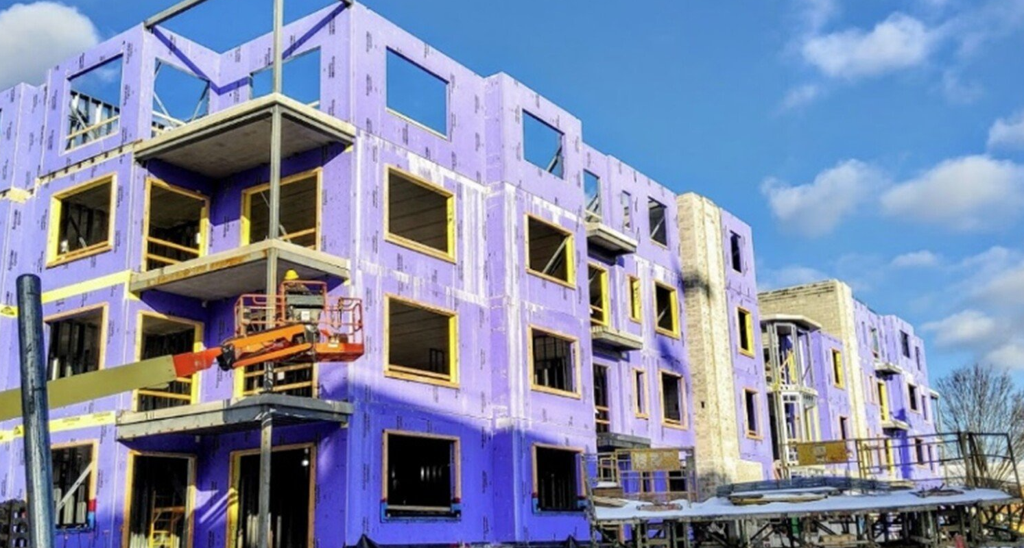 A large purple building under construction with a blue sky in the background.