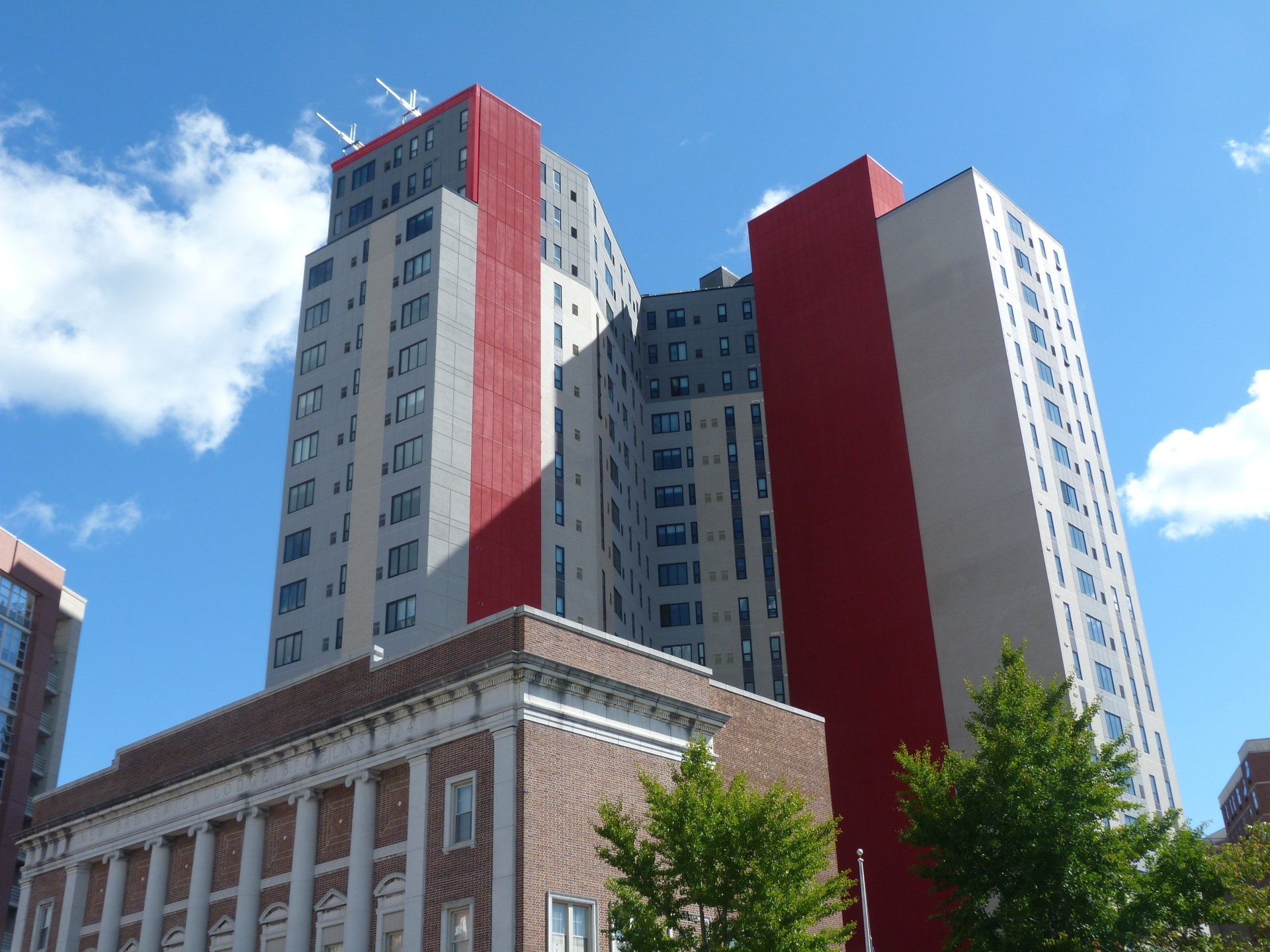 A very tall building with a red stripe and sky in the background.