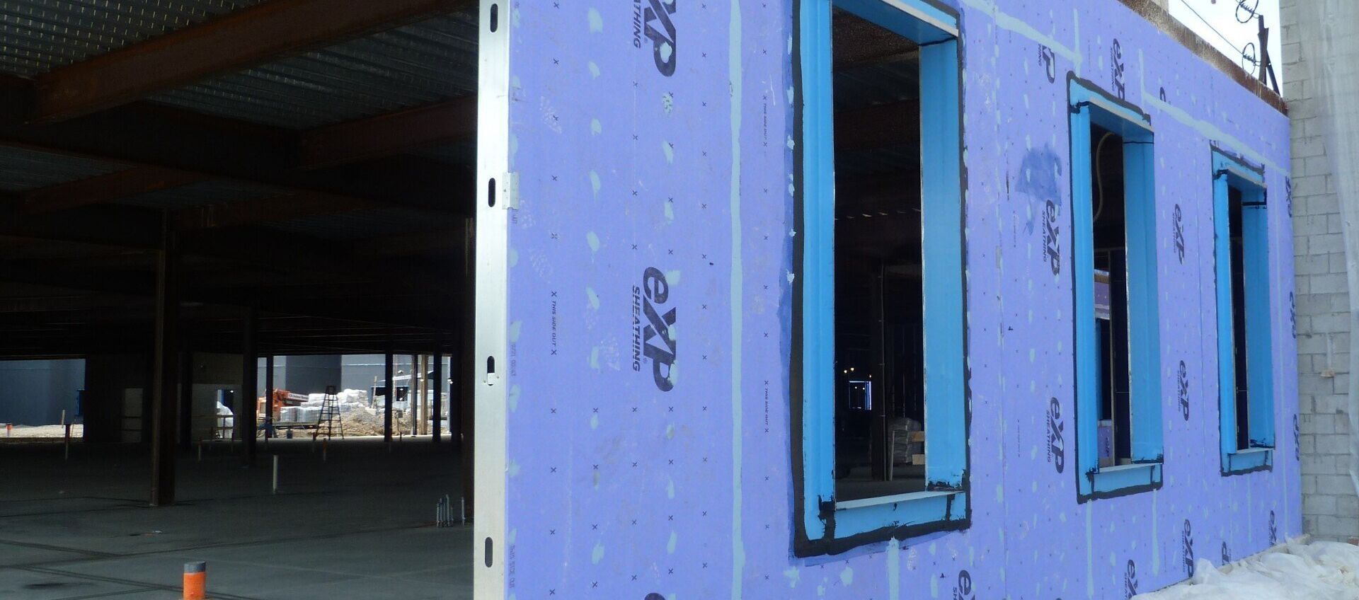 A building under construction with a purple insulation panels and windows. 