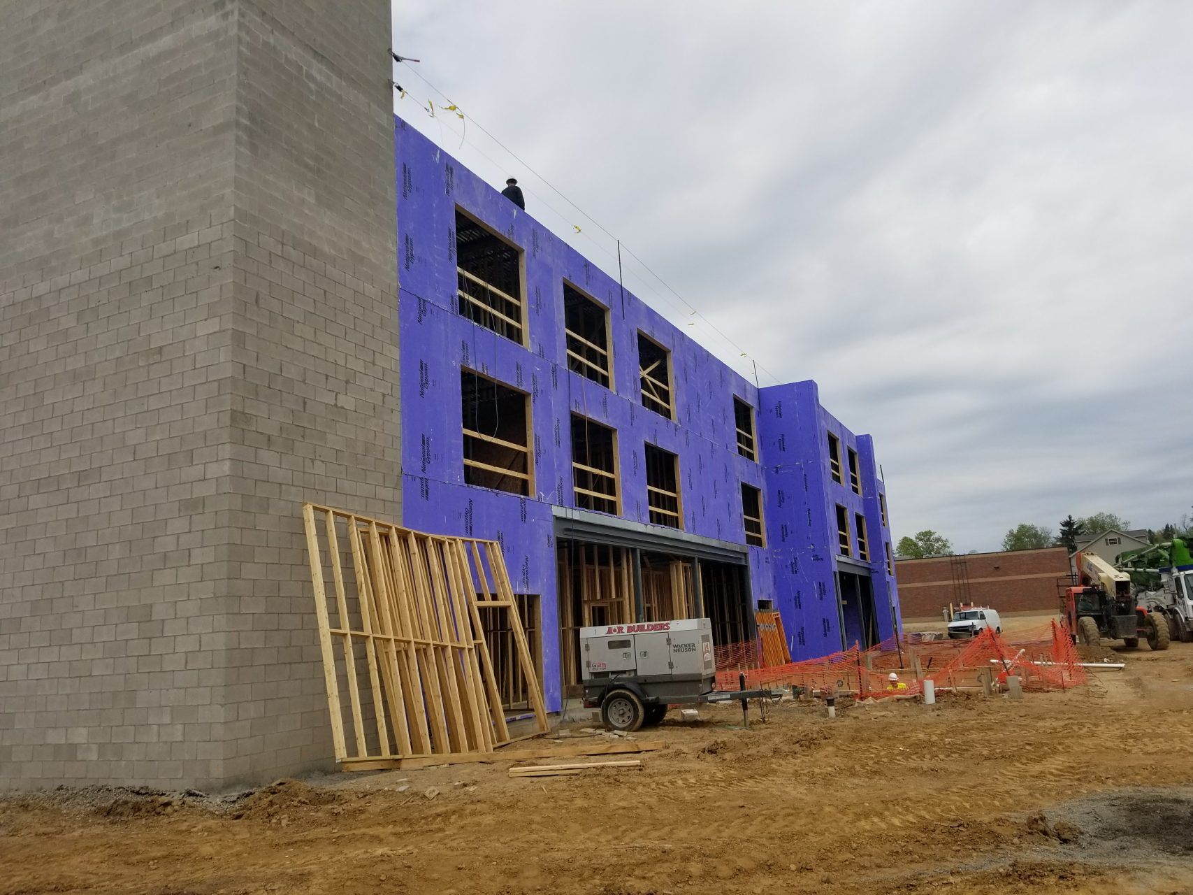 A large building is being built with purple insulation panels.