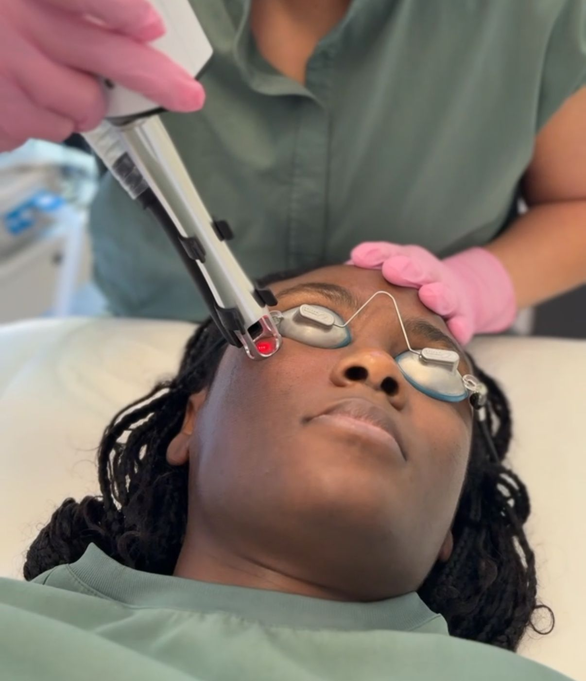 Dentist treating a patient’s eye area with a tool while another hand steadies the head