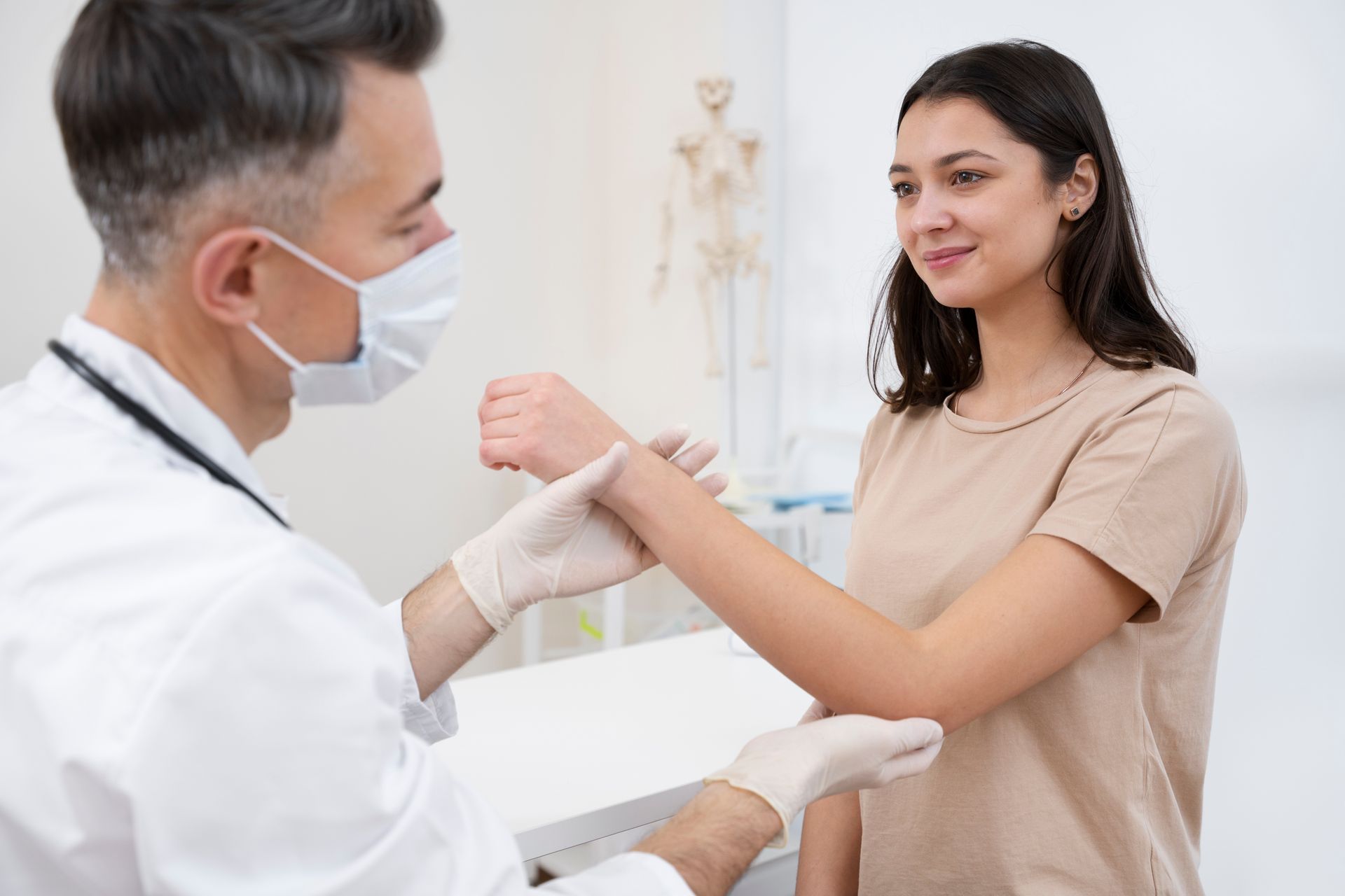 Doctor examining a patient’s wrist in a bright clinic, both wearing masks