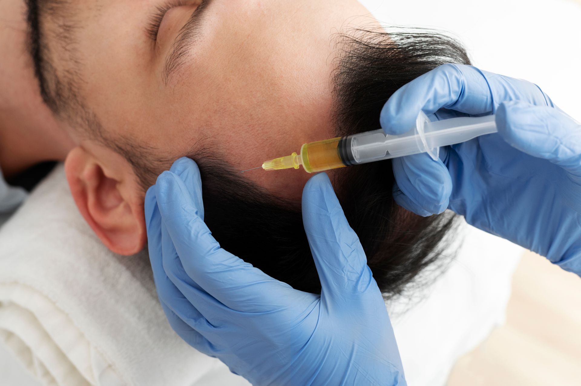 Gloved hands inject a syringe near a man’s eyebrow during a cosmetic procedure