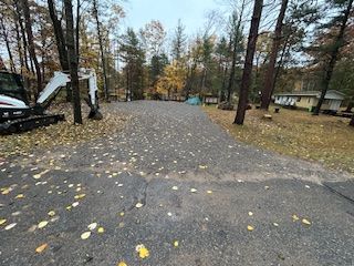 A small excavator is parked on the side of a road in the woods.