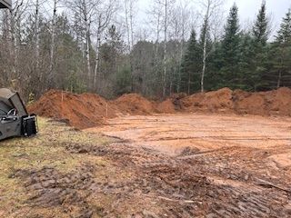 A large pile of dirt is sitting in the middle of a muddy field.