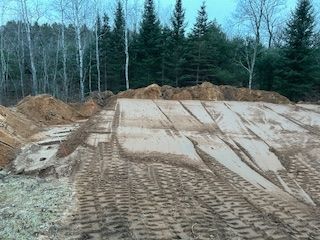 A large pile of dirt is sitting in the middle of a forest.