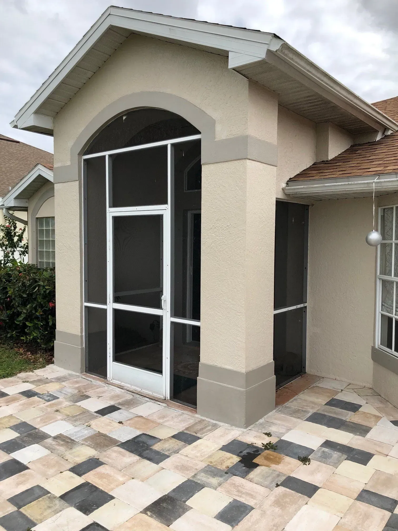 A house with a screened in porch and a tiled patio.