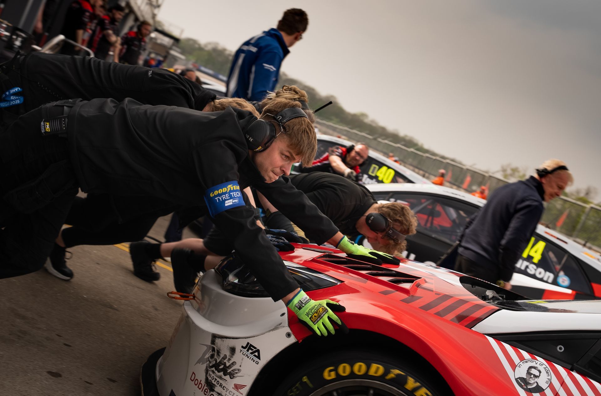 Pit crew working on a red and white race car in a pit lane.