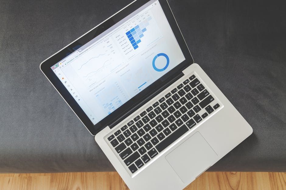 Laptop displaying charts and graphs, open on a dark surface, angled view.