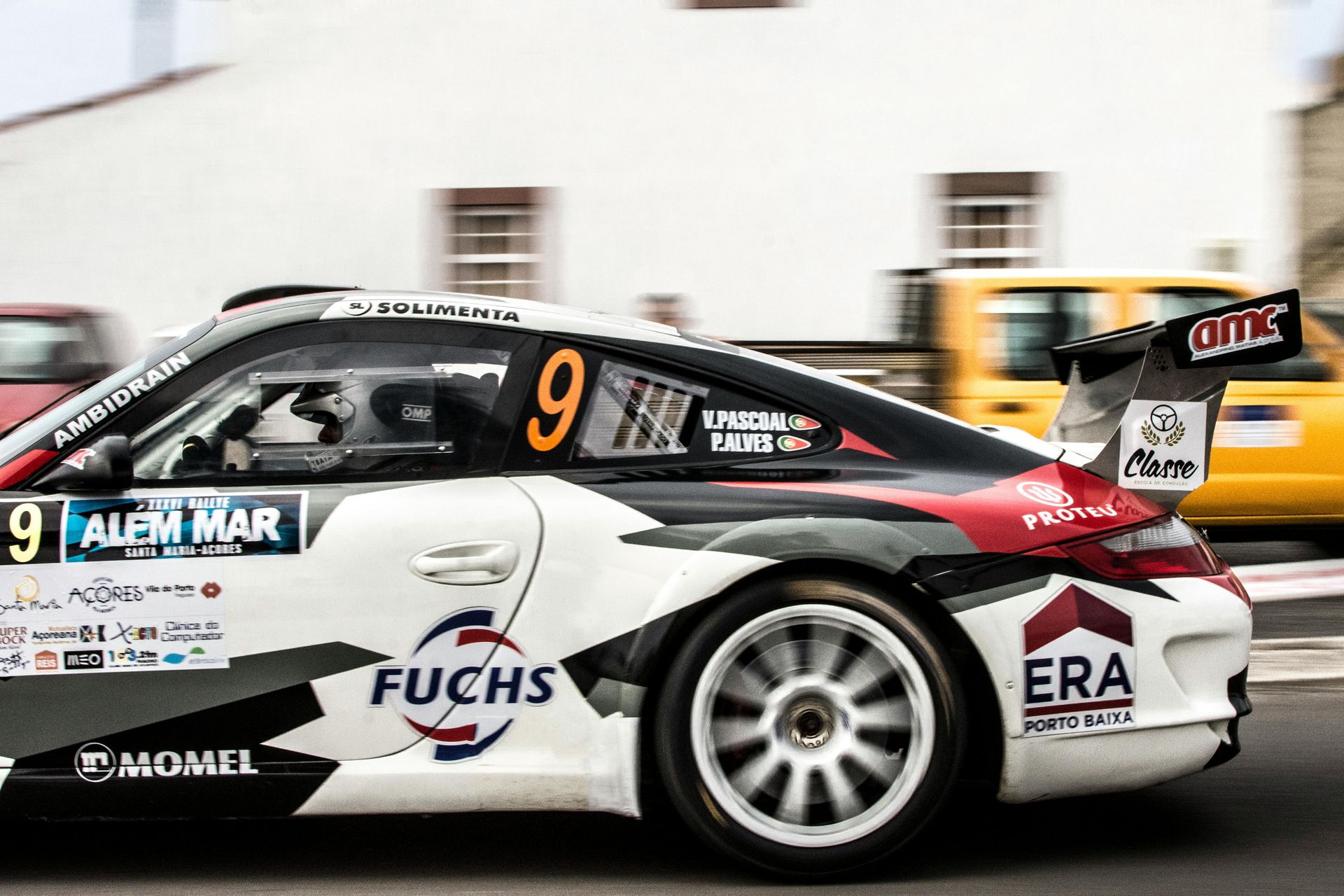 A race car with the number 9 on the side is driving down a street.