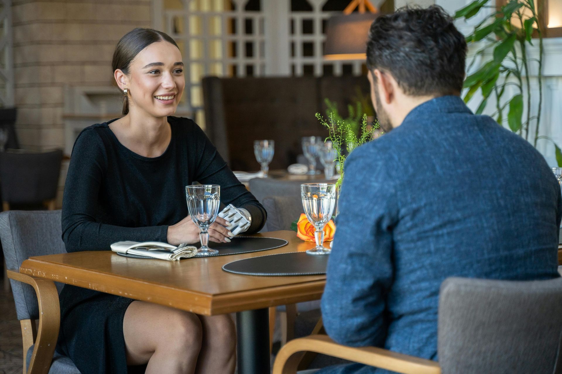 Woman smiling and talking to a person at a restaurant table.