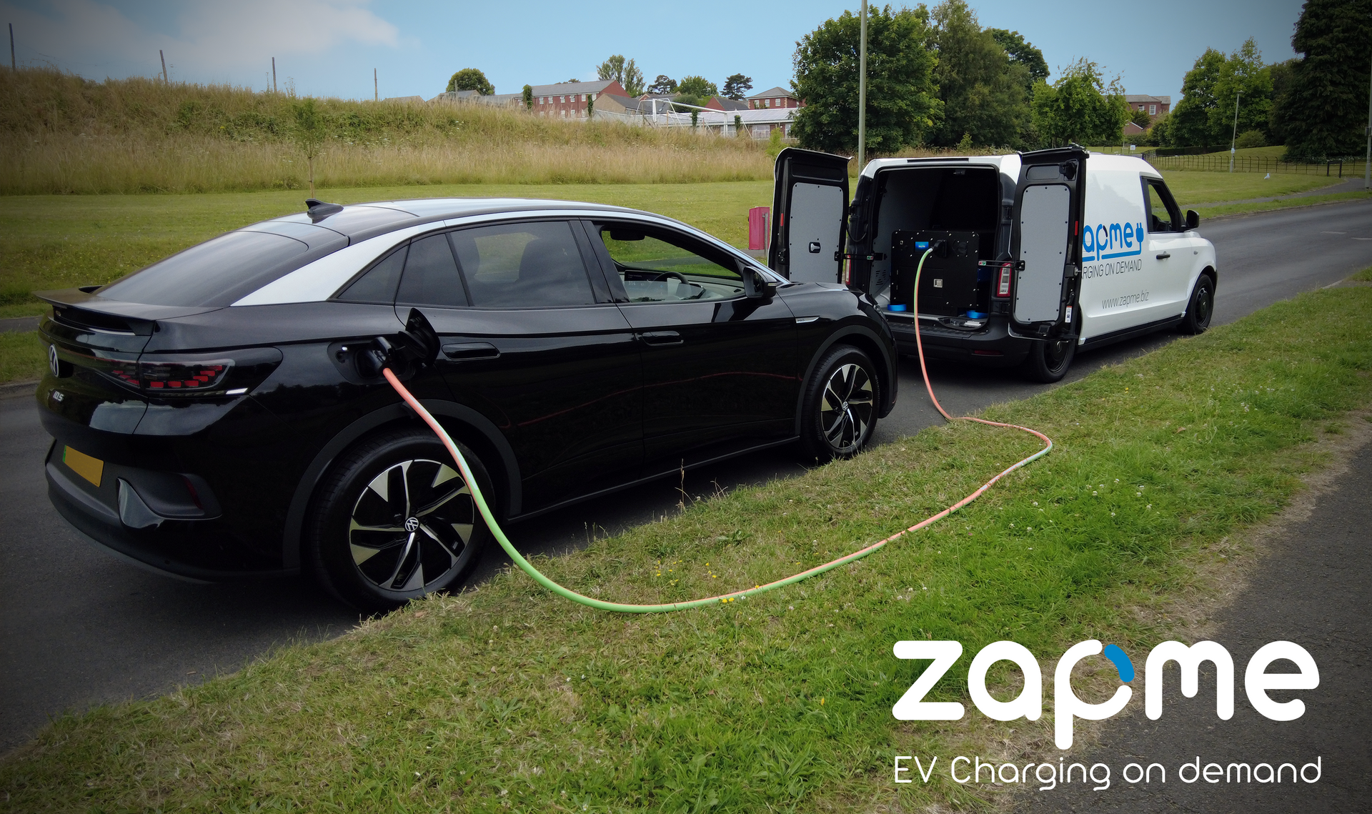 A black car is being charged by a zapme van