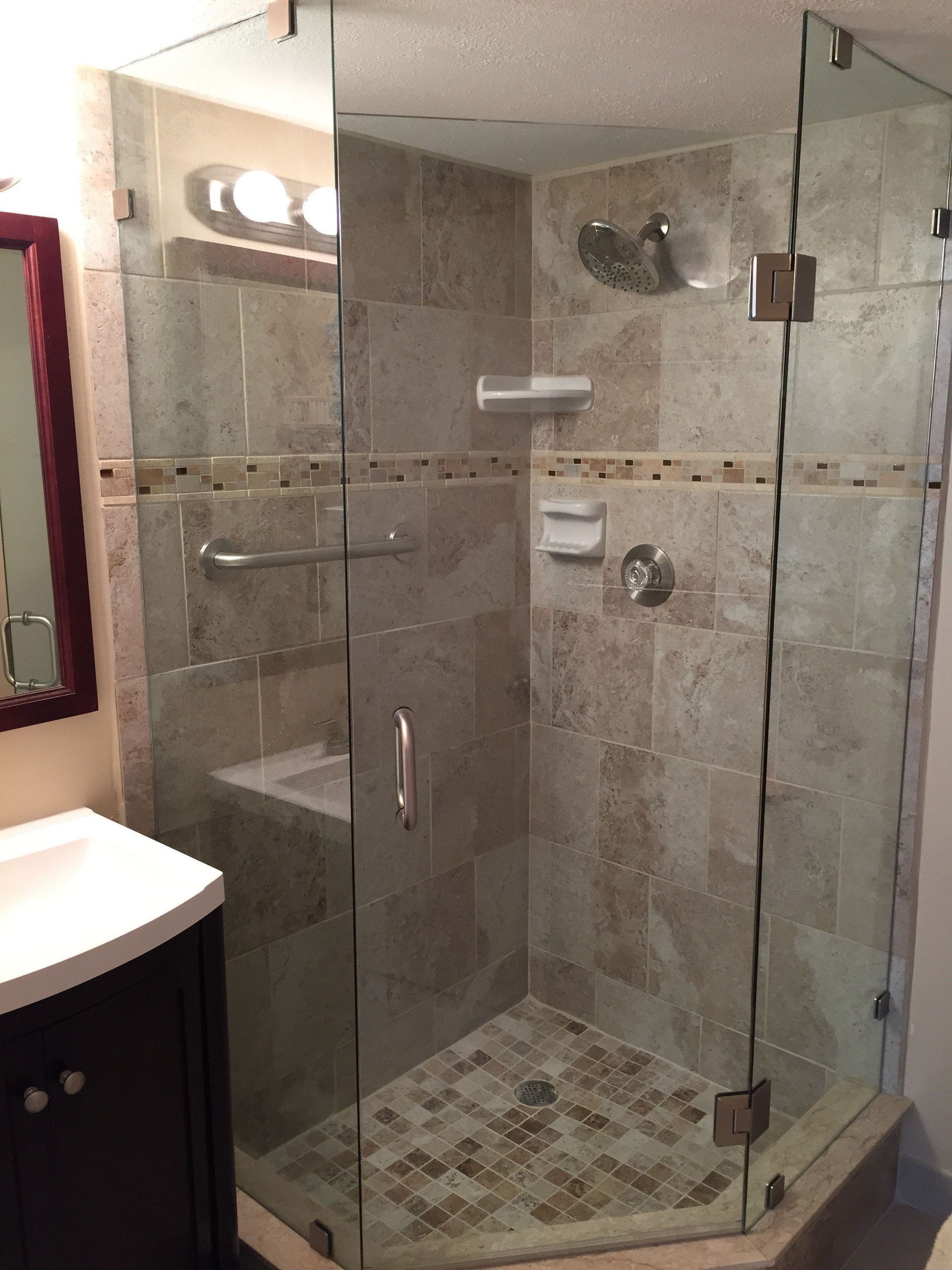 Glass corner shower with beige tile, built-in shelf, and a frosted door in a bathroom