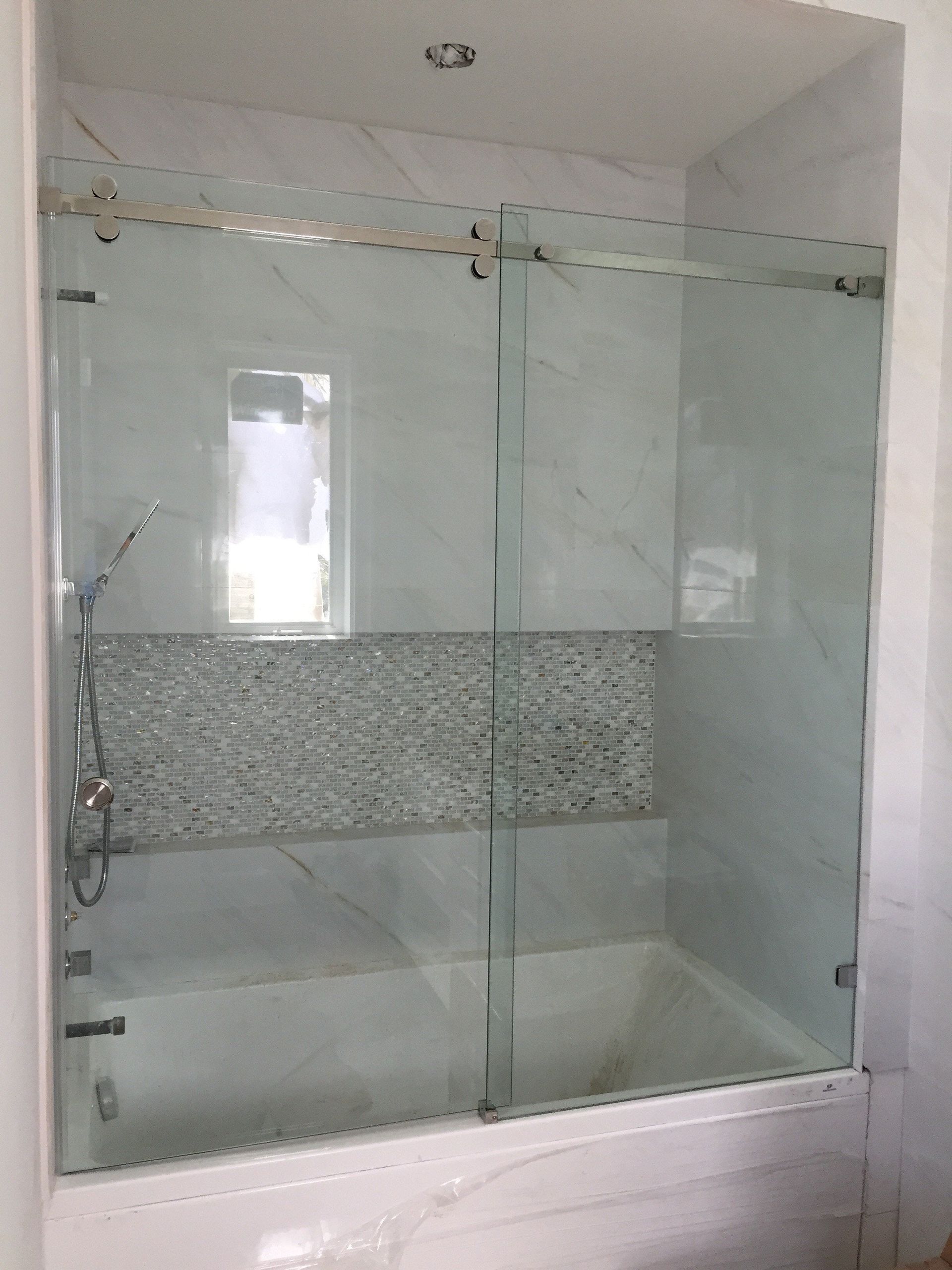 Glass shower enclosure with sliding doors and tiled wall panels