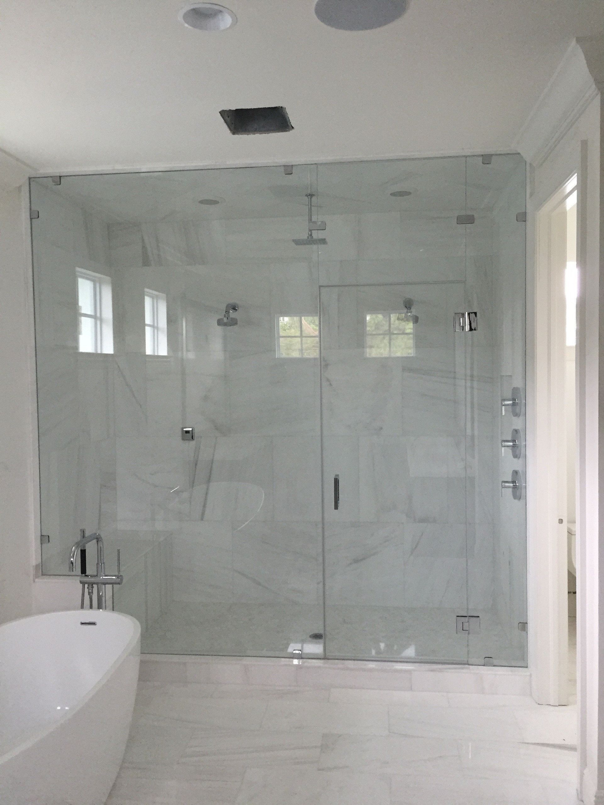 Modern bathroom with glass-enclosed shower, white tub, and light tiled walls and floor
