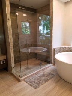 Modern bathroom with glass-enclosed shower and freestanding tub on light wood floor