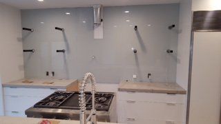 Modern kitchen with unfinished backsplash, open cabinets, and a stove beneath a range hood.