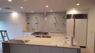 Modern kitchen under construction with unfinished island, cabinets, and exposed plumbing on the back wall
