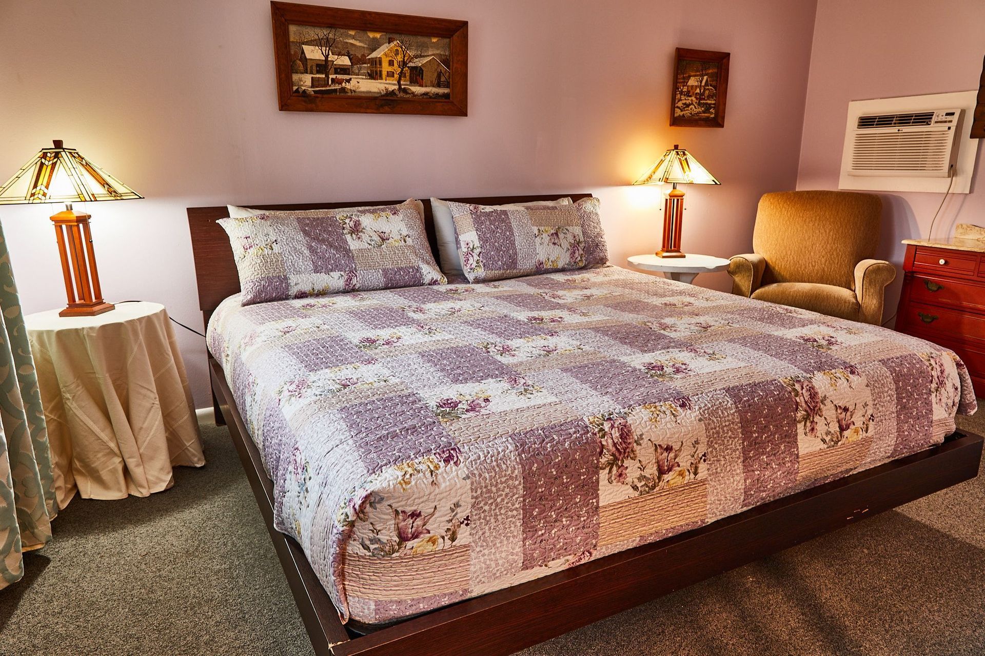 a bedroom with a king size bed , two lamps , a chair and a dresser .